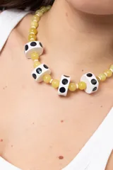 Collar corto de cuentas de piedra en tonos amarillos y verdes, intercaladas con cuentas cilíndricas blancas con lunares negros.