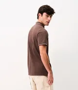 Remera polo masculina de tejido piqué marrón con textura, cuello y ribetes de mangas en tono contrastante, cierre frontal de dos botones y un bolsillo aplicado en el pecho.