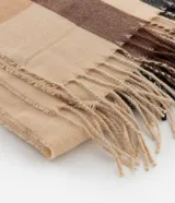 Bufanda de franela con estampado de cuadros escoceses en tonos beige, marrón y negro, con flecos en los extremos.