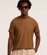 Remera marrón de corte regular, confeccionada con tejido texturizado tipo colmena, cuello redondo y manga corta.
