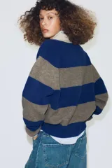Jersey de punto a rayas horizontales azules y grises, con cuello tipo polo en color beige y cierre frontal con botones.