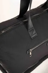 Bolso de gran capacidad color beige, con asas fijas superiores y correa de cinta negra desmontable y regulable. Presenta un bolsillo externo con cierre, un compartimento inferior con cierre y logo de la marca Daniel Cassin en el frente.