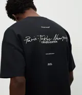 Remera de corte oversized color bordó, con cuello redondo y manga corta. Presenta un estampado en la espalda con lettering manuscrito que incluye las ciudades Paris, Tokyo y New York, junto con detalles tipográficos adicionales.