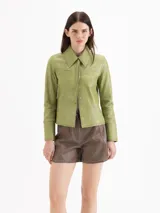 Chaqueta de cuero ovino color verde, de calce levemente entallado, cuello camisero clásico, mangas largas con puño, cierre frontal con broches a presión ocultos y dos bolsillos en la zona del busto.