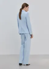 Pantalón de traje color celeste de tiro medio y diseño recto, con bolsillos laterales y cierre oculto.
