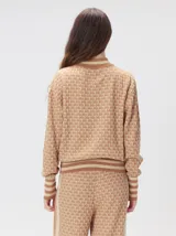 Sweater de tejido de punto jacquard con diseño geométrico, cuello redondo y puños acanalados en contraste de color verde y beige.