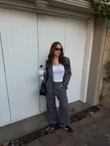Conjunto de blazer y pantalón de lino gris con diseño de rayas diplomáticas. El blazer es de corte amplio con doble botonadura, y el pantalón es de corte recto y tiro alto.