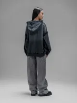 Hoodie oversize de corte crop en color gris oscuro, confeccionado en algodón rústico. Presenta un diseño con costuras expuestas, efecto de desgaste y detalles de roturas en los bordes, incluyendo puños y ruedo.