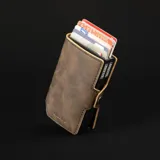 Billetera compacta de cuero sintético color marrón con doble compartimento de aluminio para tarjetas y bolsillo exterior con cierre metálico.