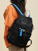 Mochila marrón con detalles en violeta. Tiene un bolsillo frontal superior con cierre, un bolsillo lateral de red y el logo de Rusty Worldwide estampado en naranja.