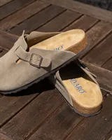 Zuecos cerrados de cuero gamuzado color beige, con tira ajustable y hebilla metálica. Presentan plantilla anatómica de corcho y látex.