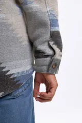 Sobrecamisa de hombre con estampado tribal en tonos gris claro, azul y marrón, de manga larga, cuello clásico, bolsillos frontales con solapa y cierre de botones.