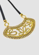 Collar con dije de flores caladas color dorado, con cadena de eslabones y tira de cuerina negra.