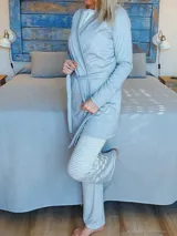 Bata de algodón gris claro, manga larga, con cruce frontal y lazo para ajustar a la cintura. Debajo se vislumbra una prenda de pijama a rayas blancas y celestes.