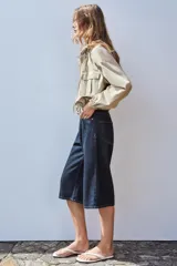 Cazadora color beige con capucha ajustable, manga larga con puño elástico, bolsillos frontales con solapa, bajo ajustable y cierre frontal con cremallera y botones a presión.