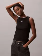 Musculosa Calvin Klein de corte slim confeccionada en tejido de canalé de algodón con elastano. Presenta cuello redondo, tirantes anchos y una etiqueta con el monograma CK en el centro del pecho.