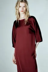 Vestido midi de Zara Woman Collection confeccionado en viscosa satinada, color bordó. Presenta cuello barco, mangas por debajo del codo y bajo recto, con detalle de lazo fino en la parte posterior del cuello.