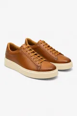 Zapato de cuero negro con diseño minimalista, cordones al tono y suela de goma blanca. Presenta un interior en color tostado que aporta un contraste sutil.
