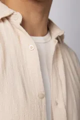 Camisa de manga larga confeccionada en tejido de lino con textura, de corte holgado y diseño versátil con cierre frontal de botones.