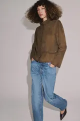 Jeans de tiro medio con corte bootcut, confeccionados en denim azul con efecto lavado y ligeros desgastes. Presentan diseño de cinco bolsillos, trabillas en la cintura y cierre frontal con cremallera y botón.