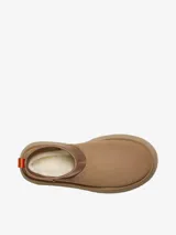 Bota corta tipo botineta de la marca UGG, color negro, con diseño de caña baja y plataforma elevada. Presenta una tira de agarre en color amarillo neón en la parte posterior y una suela de goma gruesa con textura acanalada.