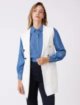 Chaleco largo tejido color blanco de la marca Sioni, con cuello solapa, doble botonadura dorada en el frente y bolsillos aplicados.