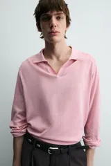 Polo de punto ligero color rosado, con cuello solapa, abertura frontal en V y manga larga.