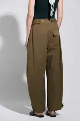 Pantalón tostado de tiro alto y silueta amplia, con costuras marcadas que aportan estructura y cierre frontal con botón metálico.
