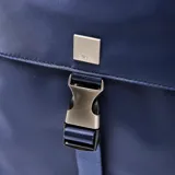 Mochila de diseño minimalista en color azul, confeccionada en material textil. Cuenta con un compartimento principal con cierre de doble cursor, un bolsillo frontal con solapa y cierre de hebilla metálica, y asa superior reforzada.
