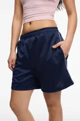 Short deportivo color bordó, confeccionado en tela satinada de poliéster. Presenta una franja lateral blanca, bolsillos laterales y cintura elastizada.