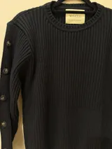 Sweater color camel de tejido de punto acanalado, con cuello redondo y botones decorativos en las mangas. Hecho en Uruguay.