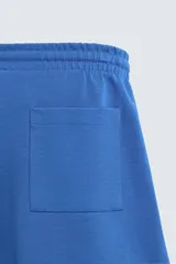 Bermuda de algodón color beige claro, corte relajado (relaxed fit), con cintura elástica ajustable mediante cordón y bolsillos laterales y trasero de plastrón.