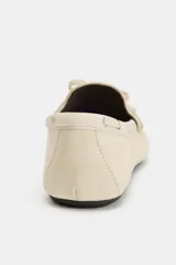Mocasín plano de piel color beige, con diseño fruncido en la parte delantera, detalle de lazo frontal y cordón lateral entrelazado con ojalillos metálicos.