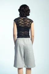 Musculosa de encaje negro con cuello alto, detalles de tiras para anudar y mangas cortas ajustadas.