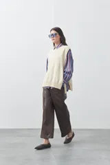 Chaleco tejido de punto con silueta relajada y diseño sin mangas. Presenta lazos laterales ajustables y cuello redondo.