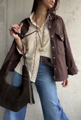 Camisa beige de tejido liviano y calce relajado, con manga larga y detalle de puntilla y bordado en contraste que recorre el frente.