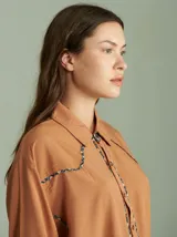 Camisa negra de algodón con mangas largas, cuello camisero y detalles de ribetes estampados a cuadros en los hombros, puños y aberturas de botones.