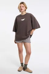 Remera de corte boxy color gris oscuro, con cuello redondo y mangas cortas. Presenta un diseño estampado localizado en la parte superior del pecho.