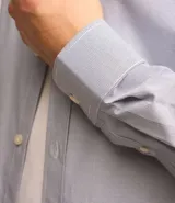 Camisa de vestir masculina de manga larga, confeccionada en tricolina con un sutil estampado de cuadros grid. Presenta cuello clásico, abotonadura frontal y puños con botones.