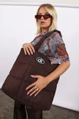 Bolso plateado acolchado con logo ovalado negro y blanco.