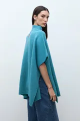 Sweater oversized color verde petróleo, con cuello alto y cierre frontal corto.