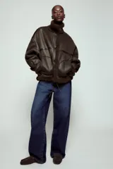 Chaqueta bomber de cuello alto con forro interior de pelo sintético. Presenta cierre frontal con botones, bolsillos delanteros y bajo ajustable con cordones.
