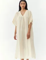 Vestido largo color crema, de corte amplio y mangas cortas.