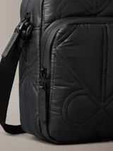 Cartera reporter Calvin Klein color negro, con diseño acolchado y pespuntes que forman el monograma de la marca. Cuenta con compartimento principal con cierre, bolsillo delantero con cremallera y correa ajustable para el hombro.