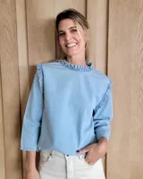 Blusa celeste de mangas 3/4 con cuello y volados en los hombros.