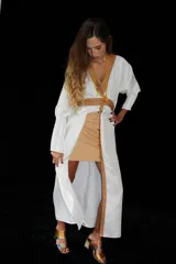 Vestido midi de silueta recta, con escote en V profundo y cuello camisero en contraste. Presenta cierre frontal con botones, mangas largas con leve volumen y tajos laterales. Diseño versátil que puede utilizarse como vestido o como camisero.