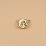 Anillo plateado con un dije redondo dorado con la figura de un ángel querubín.