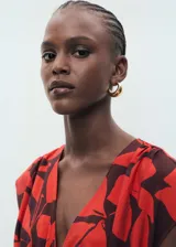 Vestido midi de corte evasé con estampado botánico en tonos rojo y marrón. Presenta cuello de pico, mangas cortas y un panel fruncido en la cintura con cordón ajustable.