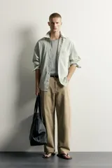 Pantalón relaxed fit de color beige, confeccionado en tejido con mezcla de algodón y lino, con diseño de cinco bolsillos, efecto lavado y cierre frontal con cremallera y botón.