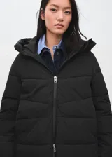 Chaqueta puffer acolchada color negro, con diseño recto, cuello alto y capucha. Cuenta con manga larga con puños elásticos, bolsillos laterales con cierre de cremallera y cierre frontal de cremallera doble. Incorpora acabado repelente al agua.